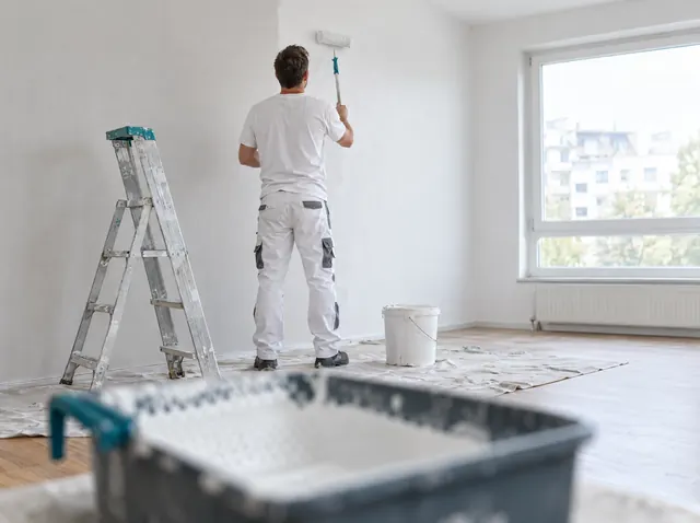 Maler streicht eine Wand mit der Farbrolle, Symbolbild zum Ratgeber „Gründungszuschuss: Arbeitsagentur oder Jobcenter?“