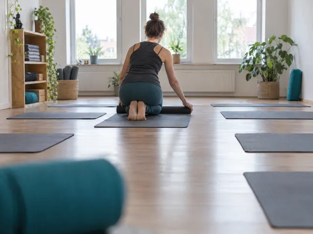 Yogalehrerin legt Matten in ihrem Studio aus, Symbolbild zum Ratgeber „Gründungszuschuss: Steuern und Krankenversicherung“