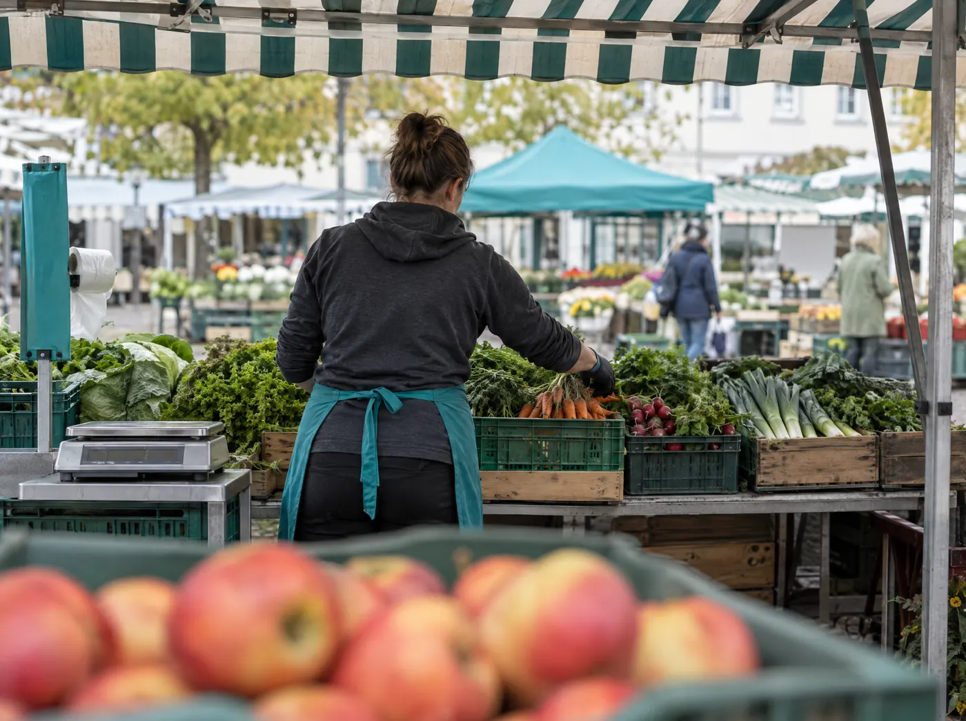 Händlerin richtet Gemüse an ihrem Wochenmarktstand, Symbolbild zum Ratgeber „Markt- und Wettbewerbsanalyse im Businessplan“